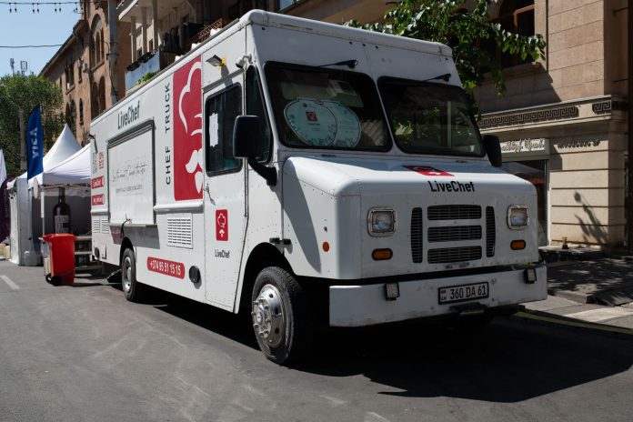 White food truck by LiveChef at a bustling street festival under sunny skies.