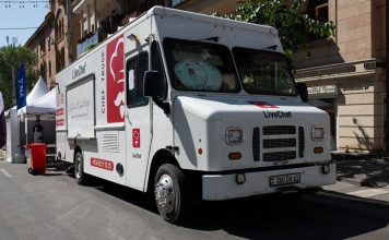 White food truck by LiveChef at a bustling street festival under sunny skies.