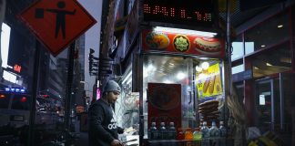 Urban street food vendor serving at night in New York City, capturing the bustling nightlife.