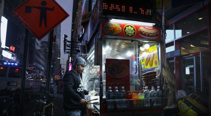 Urban street food vendor serving at night in New York City, capturing the bustling nightlife.