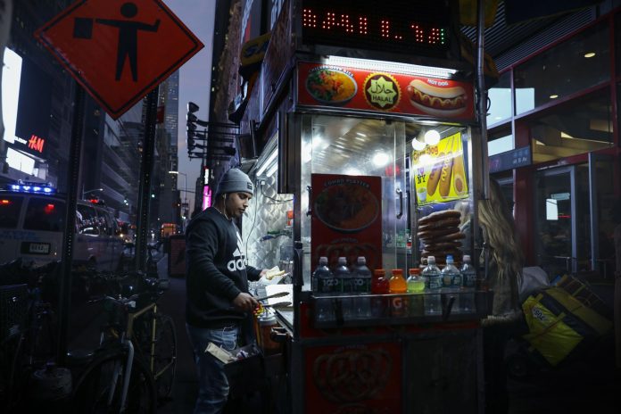 Urban street food vendor serving at night in New York City, capturing the bustling nightlife.