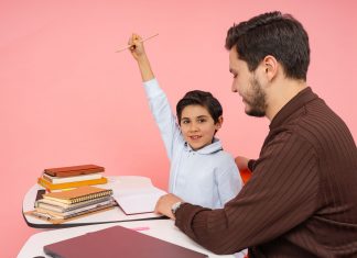 Teacher aids enthusiastic student in classroom setting, enhancing learning experience.
