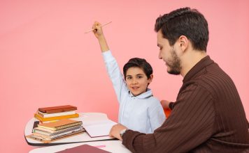 Teacher aids enthusiastic student in classroom setting, enhancing learning experience.