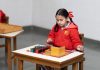 A young girl in a classroom focused on a Montessori educational activity with colorful blocks.