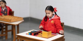 A young girl in a classroom focused on a Montessori educational activity with colorful blocks.