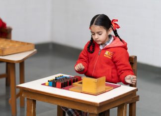 A young girl in a classroom focused on a Montessori educational activity with colorful blocks.
