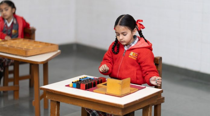 A young girl in a classroom focused on a Montessori educational activity with colorful blocks.