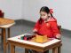 A young girl in a classroom focused on a Montessori educational activity with colorful blocks.