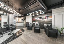 Comfortable backwash chairs with sinks near potted plant placed in contemporary beauty salon with bright illumination and abundance of cosmetology products