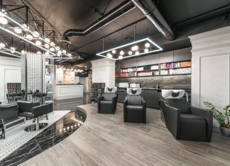 Comfortable backwash chairs with sinks near potted plant placed in contemporary beauty salon with bright illumination and abundance of cosmetology products