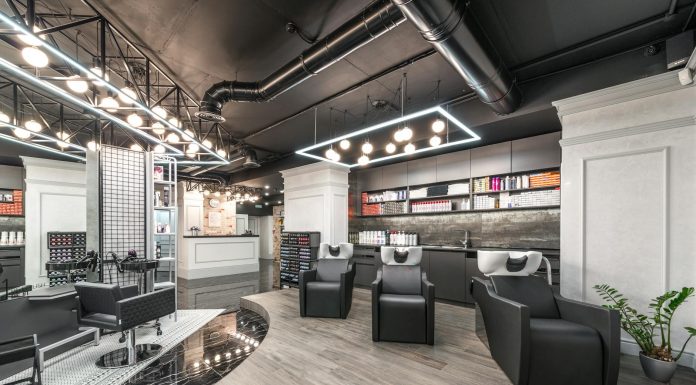Comfortable backwash chairs with sinks near potted plant placed in contemporary beauty salon with bright illumination and abundance of cosmetology products