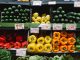 Colorful assortment of fresh vegetables at a supermarket display, highlighting peppers, squash, and cucumbers.