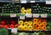 Colorful assortment of fresh vegetables at a supermarket display, highlighting peppers, squash, and cucumbers.