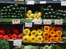 Colorful assortment of fresh vegetables at a supermarket display, highlighting peppers, squash, and cucumbers.