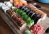 A delicious selection of sushi rolls with toppings like seaweed and sesame seeds on a wooden platter.