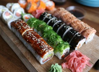 A delicious selection of sushi rolls with toppings like seaweed and sesame seeds on a wooden platter.