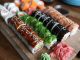 A delicious selection of sushi rolls with toppings like seaweed and sesame seeds on a wooden platter.