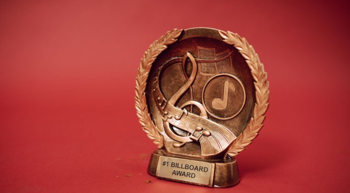 A close-up of a golden music award trophy against a vibrant red background.
