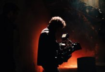 BREAKING: 1888 Studios in Bayonne Wins Major Real Estate Award A professional cameraman captures footage in a creatively lit, moody setting, backlit by warm light.