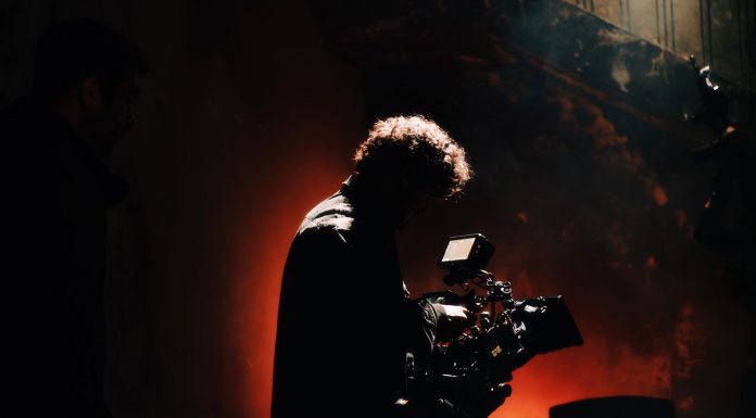 BREAKING: 1888 Studios in Bayonne Wins Major Real Estate Award A professional cameraman captures footage in a creatively lit, moody setting, backlit by warm light.