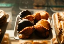 Warm-toned close-up of assorted pastries in a bakery display, sunlight highlighting texture.