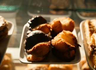 Warm-toned close-up of assorted pastries in a bakery display, sunlight highlighting texture.