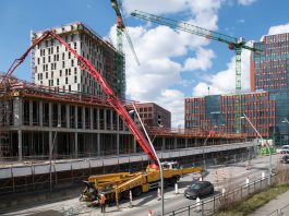 Busy construction site in Hamburg with cranes and trucks under a clear sky.