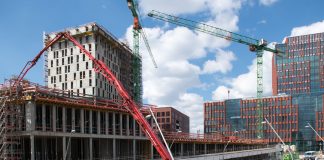 Busy construction site in Hamburg with cranes and trucks under a clear sky.