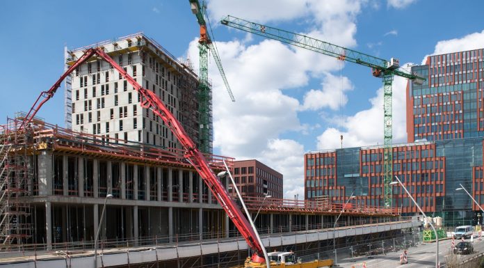 Busy construction site in Hamburg with cranes and trucks under a clear sky.