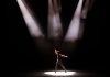 Energetic performance by male dancer under dramatic stage lighting.