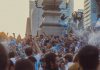 Joyful crowd celebrating soccer victory with flags in Mexico City streets.