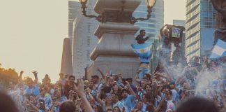 Joyful crowd celebrating soccer victory with flags in Mexico City streets.