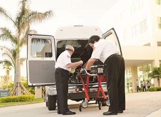 BREAKING: Jersey City Medical Center Sees Surge in Patients After HUH Closure Two paramedics load medical equipment into a white ambulance outside a hospital in a tropical setting.