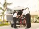 BREAKING: Jersey City Medical Center Sees Surge in Patients After HUH Closure Two paramedics load medical equipment into a white ambulance outside a hospital in a tropical setting.
