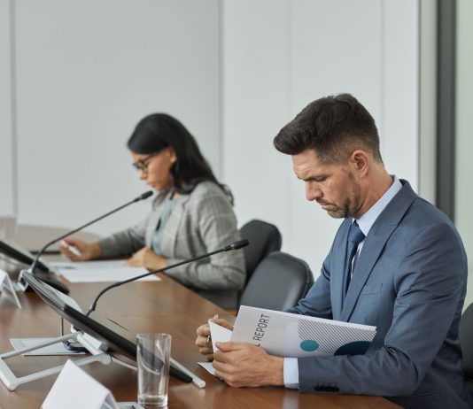 Business professionals in a conference setting, focusing on documents and reports.