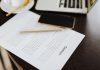 Close-up of a contract with office essentials like a laptop and coffee on a desk.