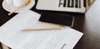 Close-up of a contract with office essentials like a laptop and coffee on a desk.
