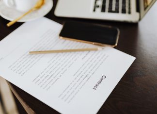BREAKING: Jersey City School Board to Vote on Superintendent’s Contract Close-up of a contract with office essentials like a laptop and coffee on a desk.