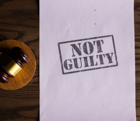 A courtroom document labeled 'Not Guilty' beside a gavel symbolizes justice.