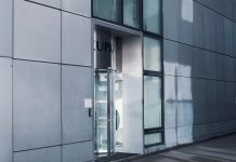 Sleek modern architecture featuring a glass entrance with reflective facade, showcasing contemporary design.