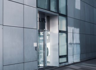 Sleek modern architecture featuring a glass entrance with reflective facade, showcasing contemporary design.