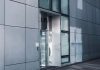 Sleek modern architecture featuring a glass entrance with reflective facade, showcasing contemporary design.
