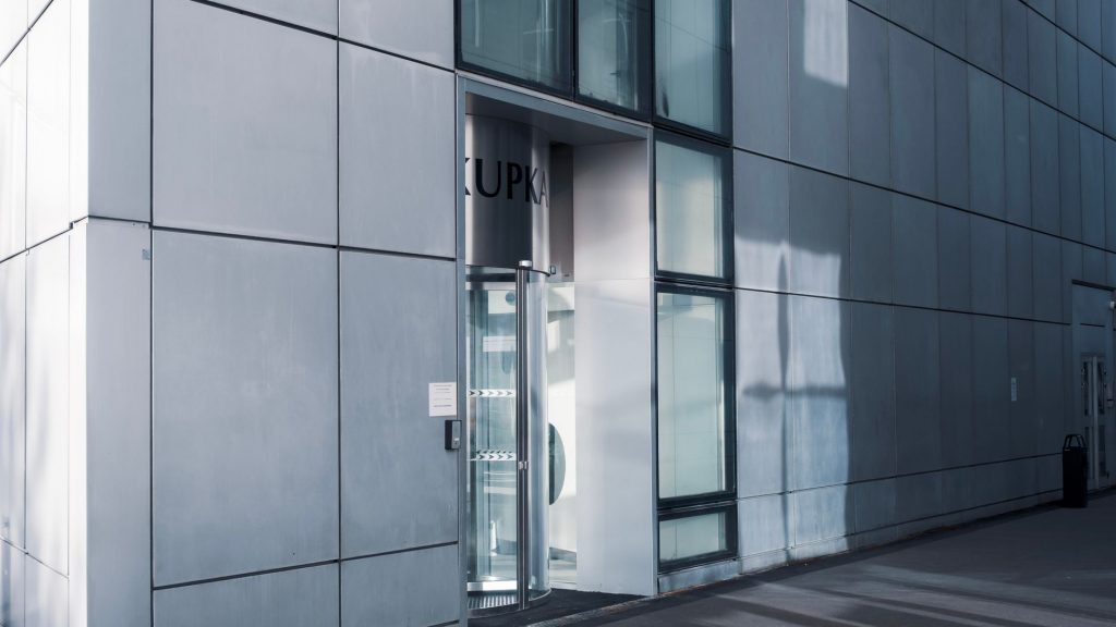 Sleek modern architecture featuring a glass entrance with reflective facade, showcasing contemporary design.