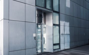 BREAKING: NJ Opens Free Office Space in Jersey City to Lure Foreign Firms Sleek modern architecture featuring a glass entrance with reflective facade, showcasing contemporary design.