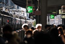 Crowd at Osaka train station platform with train in view, showcasing urban travel hustle.