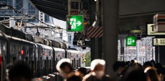 Crowd at Osaka train station platform with train in view, showcasing urban travel hustle.