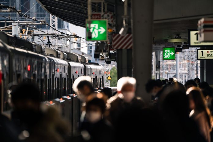 Crowd at Osaka train station platform with train in view, showcasing urban travel hustle.