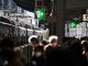 Crowd at Osaka train station platform with train in view, showcasing urban travel hustle.