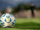 Close-up of an official Argentine soccer ball resting on a green field with a blurred background.