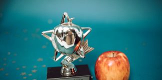 Silver star-shaped trophy with apple on a blue background for teacher appreciation.